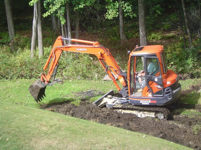Compact Excavator burying large boulders