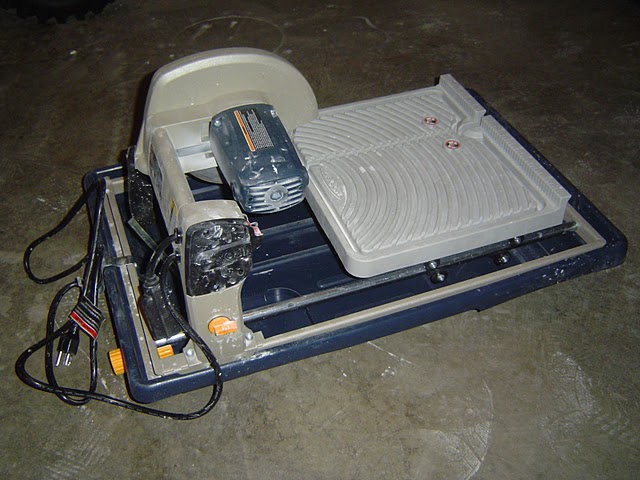 Higher end tile saw with motor/saw unit above table and water tray.