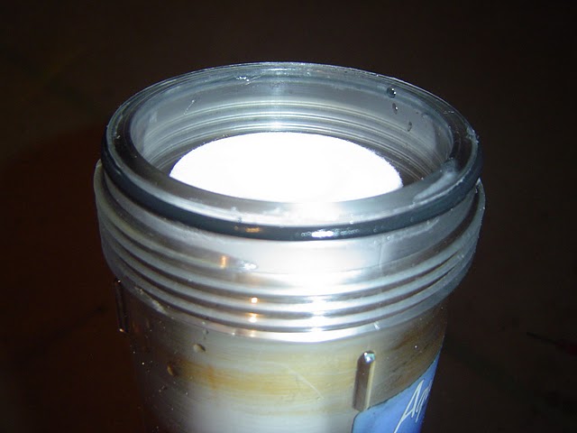 Water filter cartridge replacement inserted into base unit of whole house water filter. Notice O-ring on lip of base unit.
